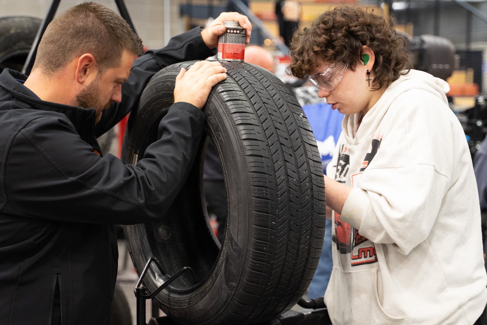 Instructor helps a student examine a car tire.