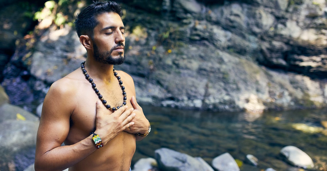 man doing gratitude meditation next to a creek