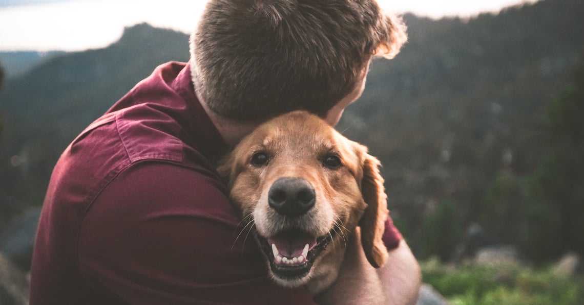 man outddors, hugging his dog