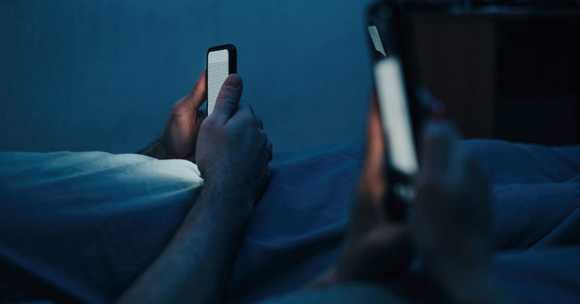 a couple in bed looking at their phones