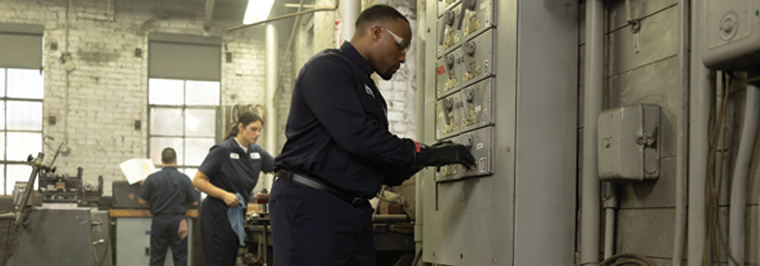 Team of employees wearing navy FR workwear in industrial environment