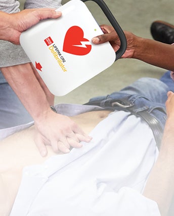 Employees helping a coworker during a workplace accident using AED LIFEPAK® CR2