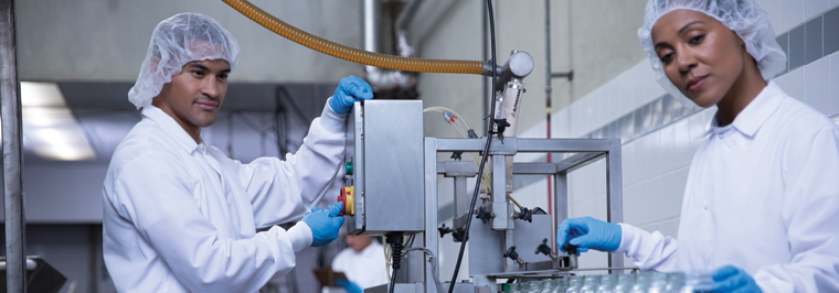 Employees working in a food processing facility wearing workwear from a HACCP uniform program
