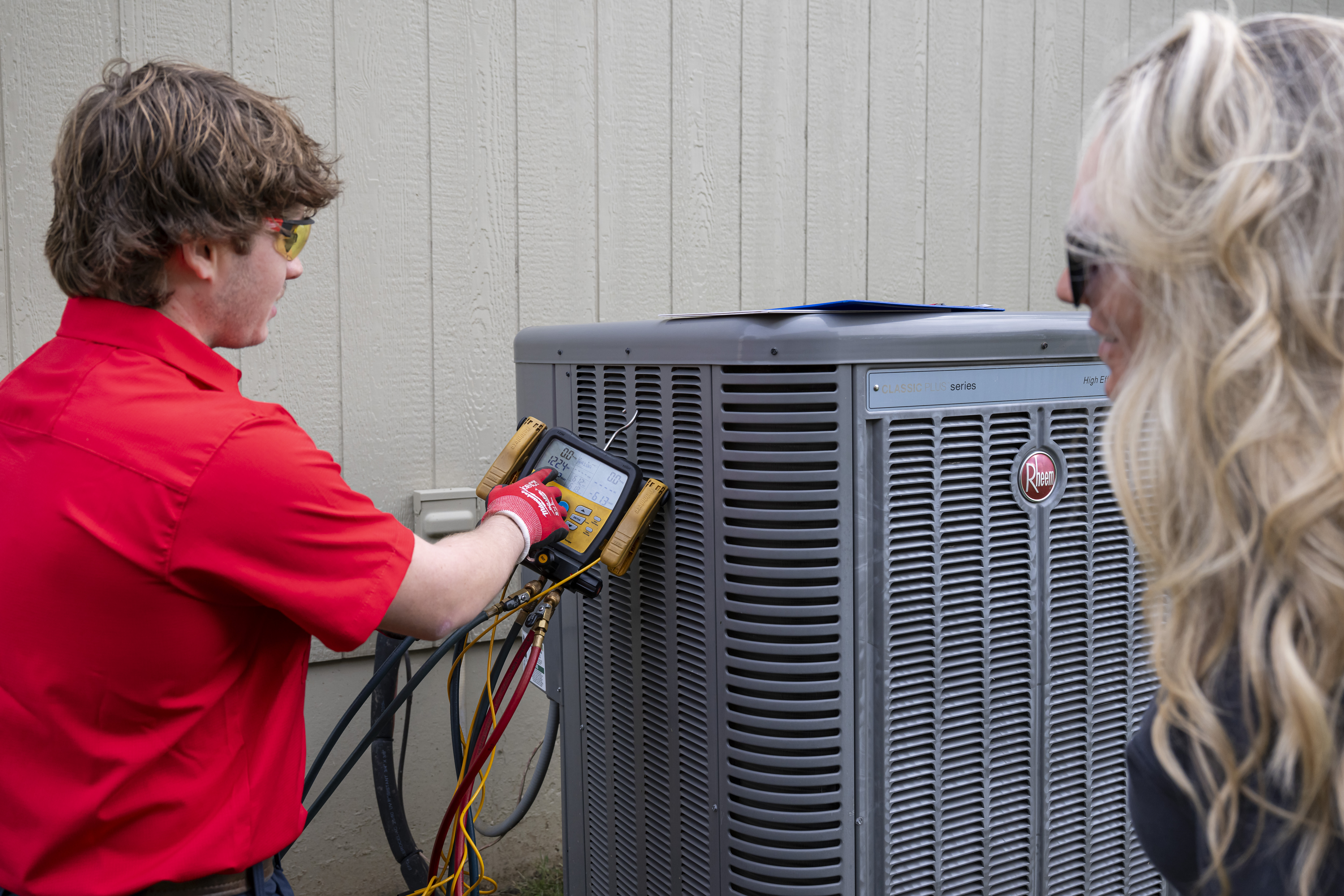 Patriot Heating & AC technician showing gauge readings to a homeowner during a system check