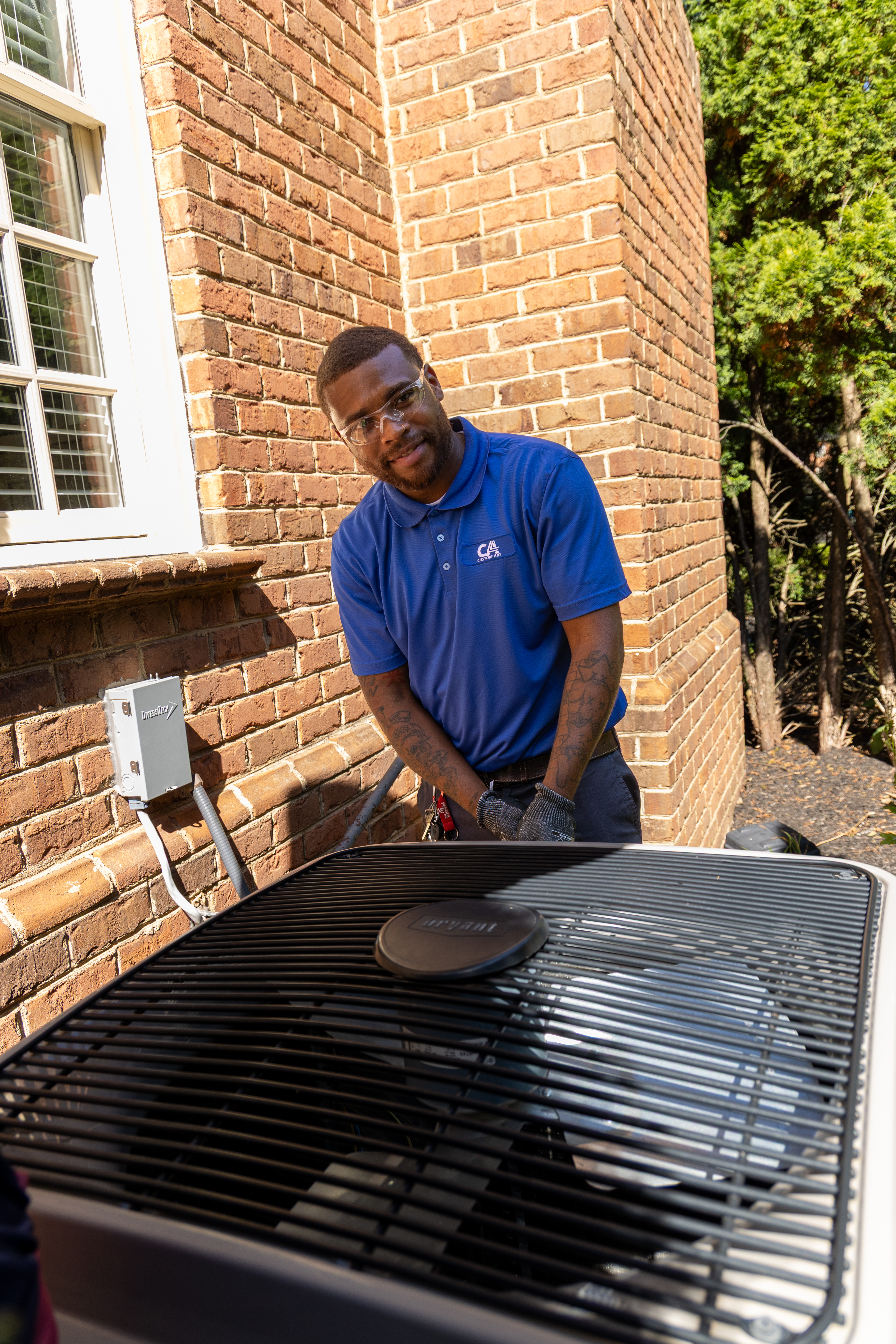 Custom Air technician servicing an outdoor AC condenser at a customer's home