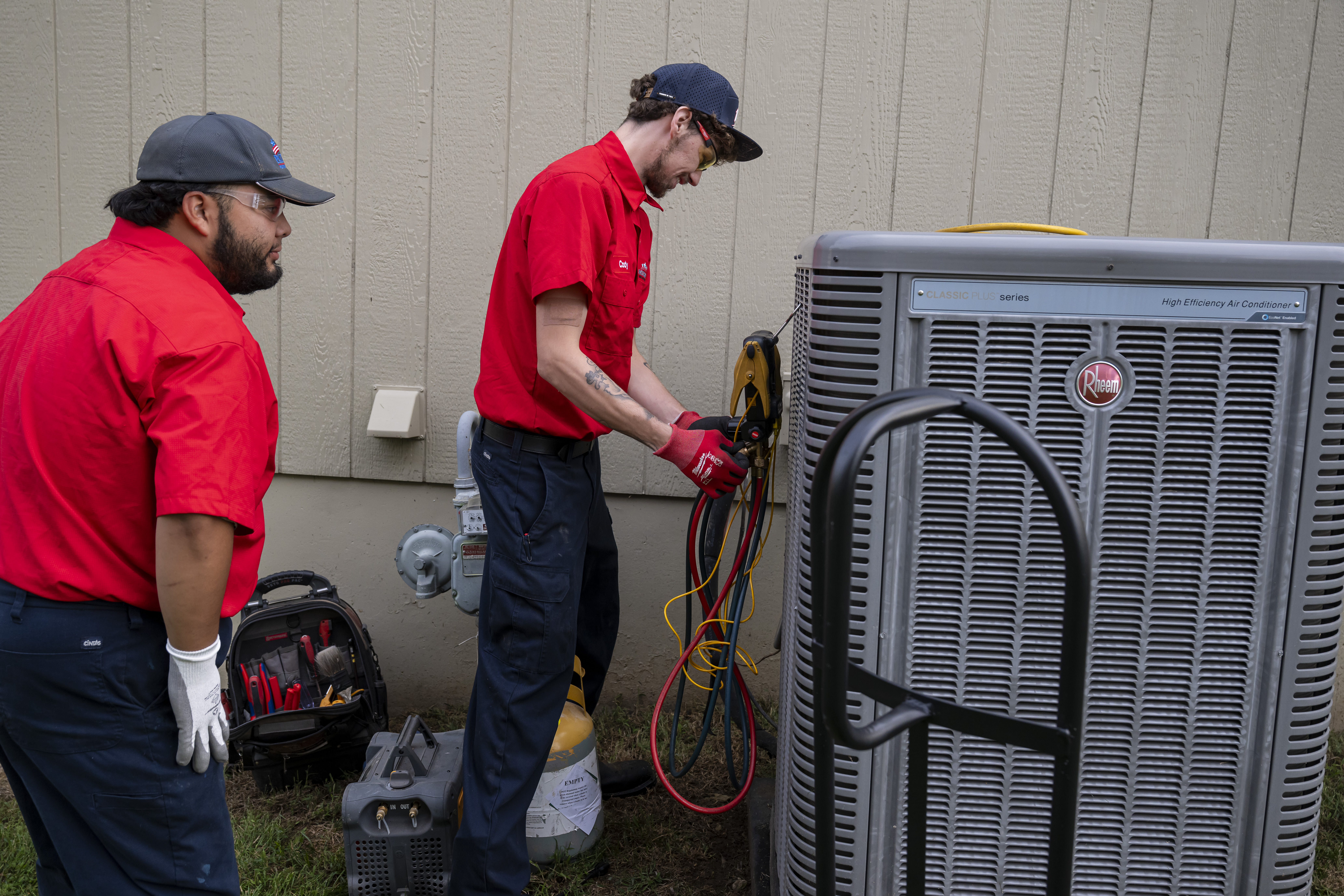 Two Patriot Heating & AC technicians working on an outdoor air conditioning unit