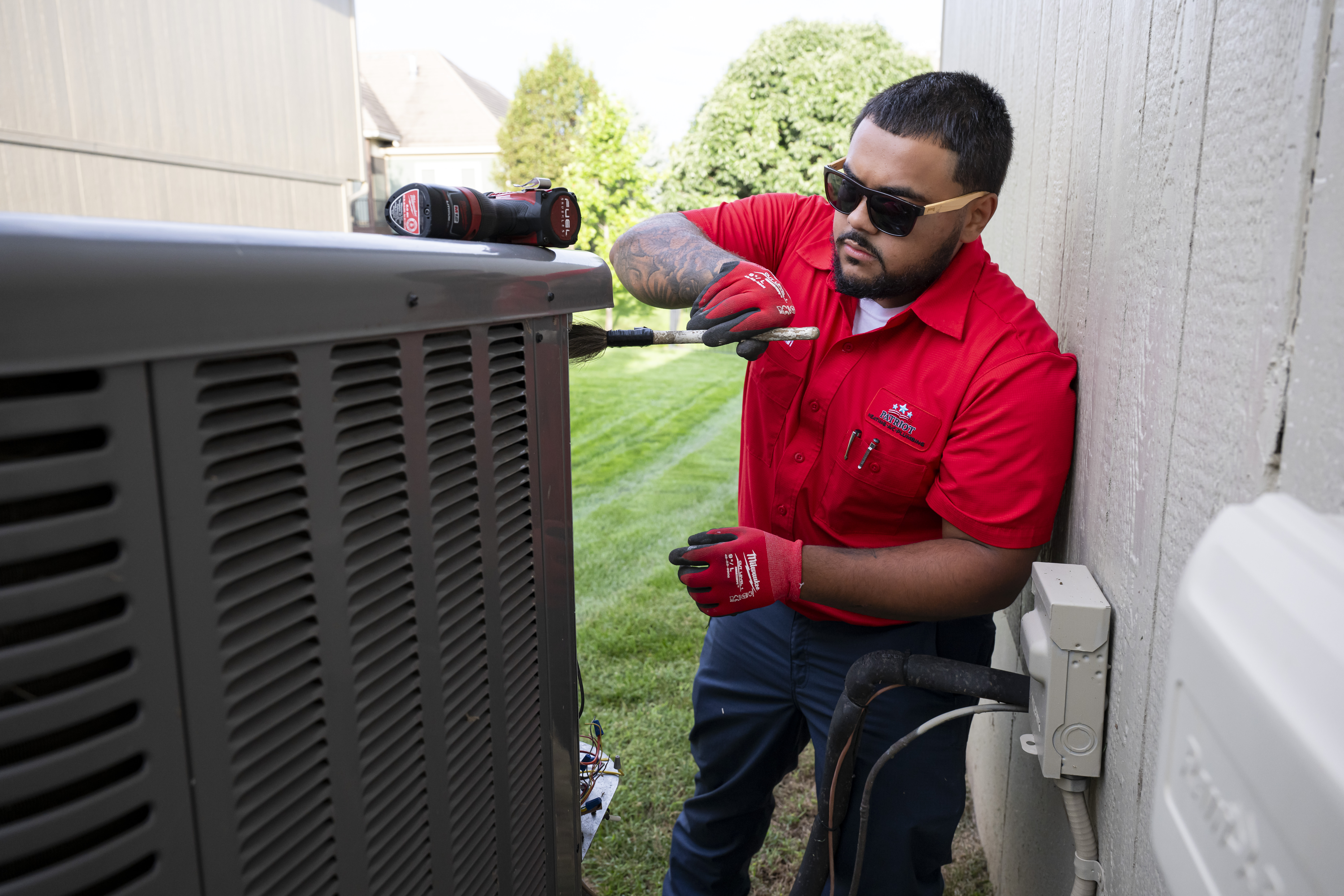 Patriot Heating & AC technician servicing an outdoor air conditioning unit
