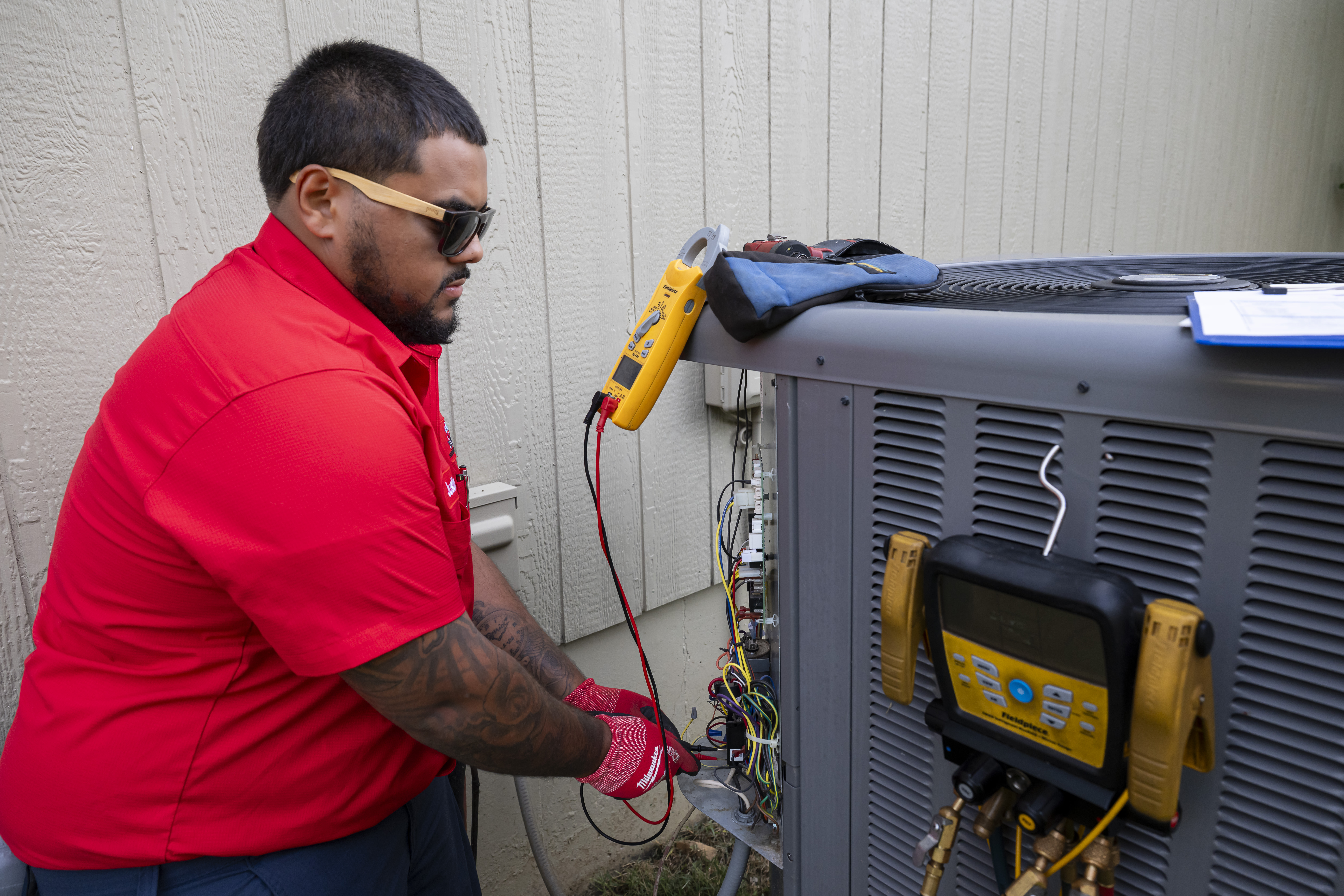 Patriot Heating & AC technician diagnosing an air conditioner with gauges and a meter
