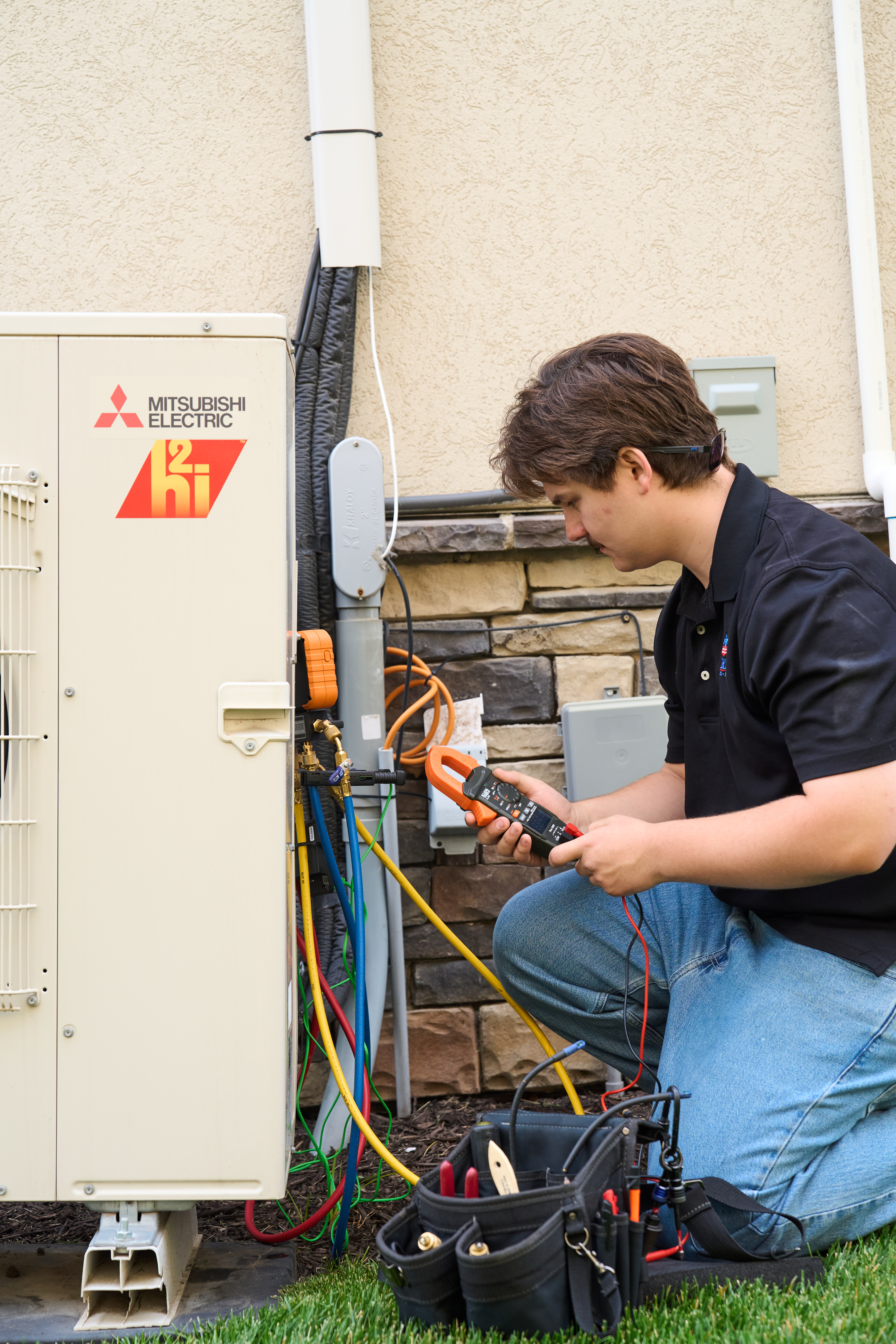Patriot Heating & AC technician servicing a Mitsubishi Electric ductless mini-split outdoor unit