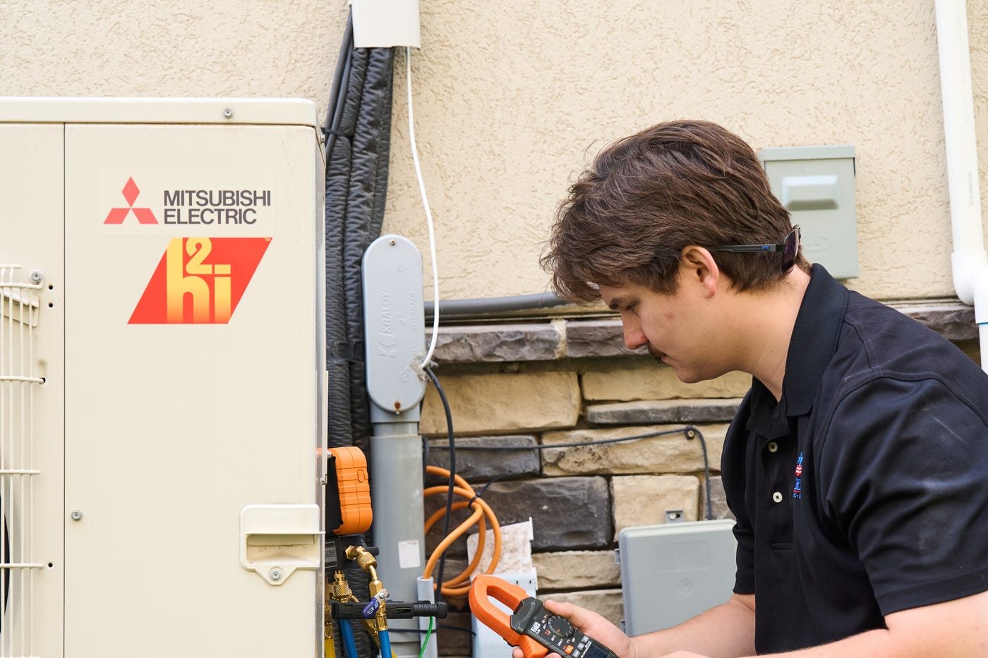 Patriot Heating & AC technician servicing a Mitsubishi Electric ductless mini-split outdoor unit