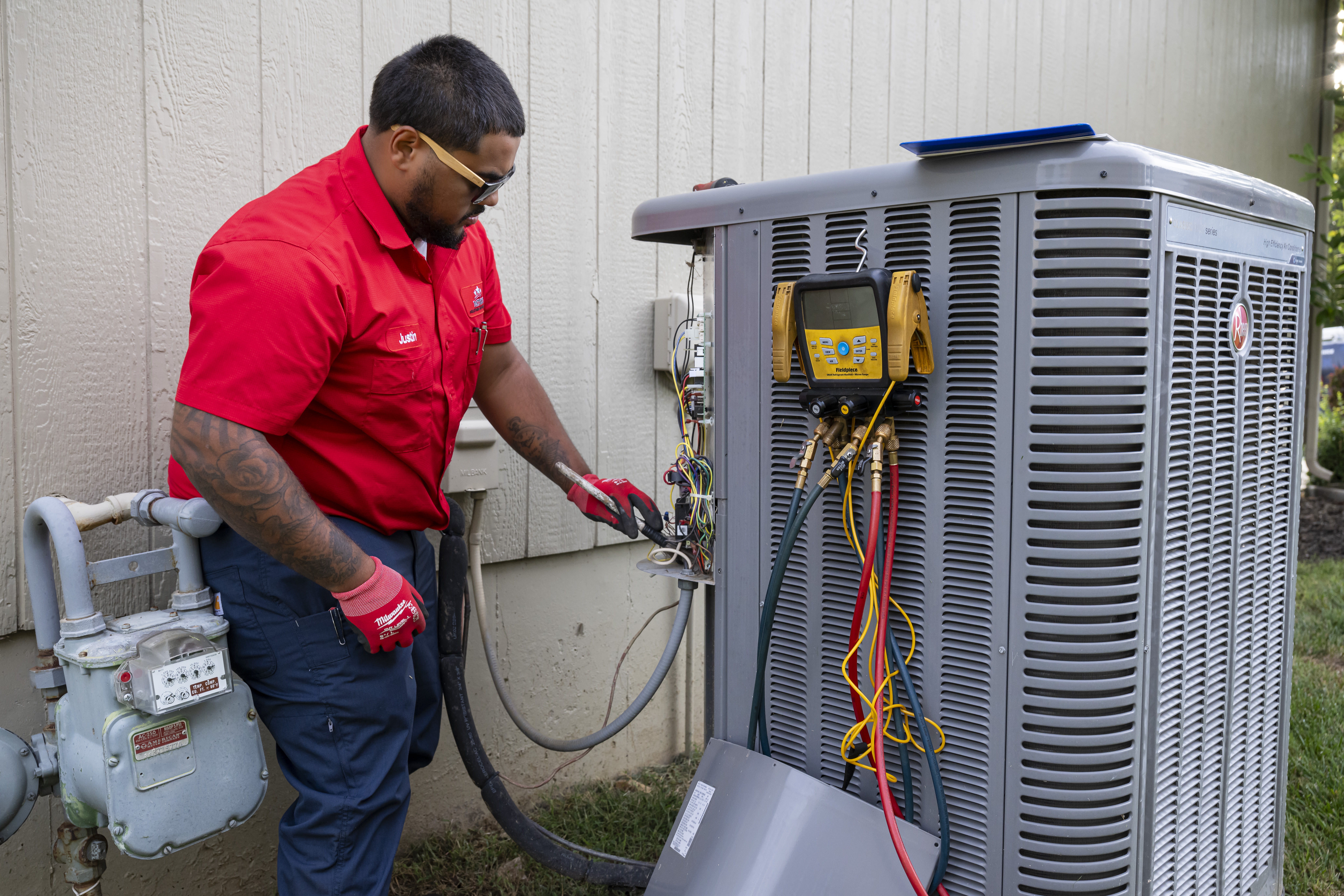 Patriot Heating & AC technician checking refrigerant pressures on an air conditioner during a tune-up