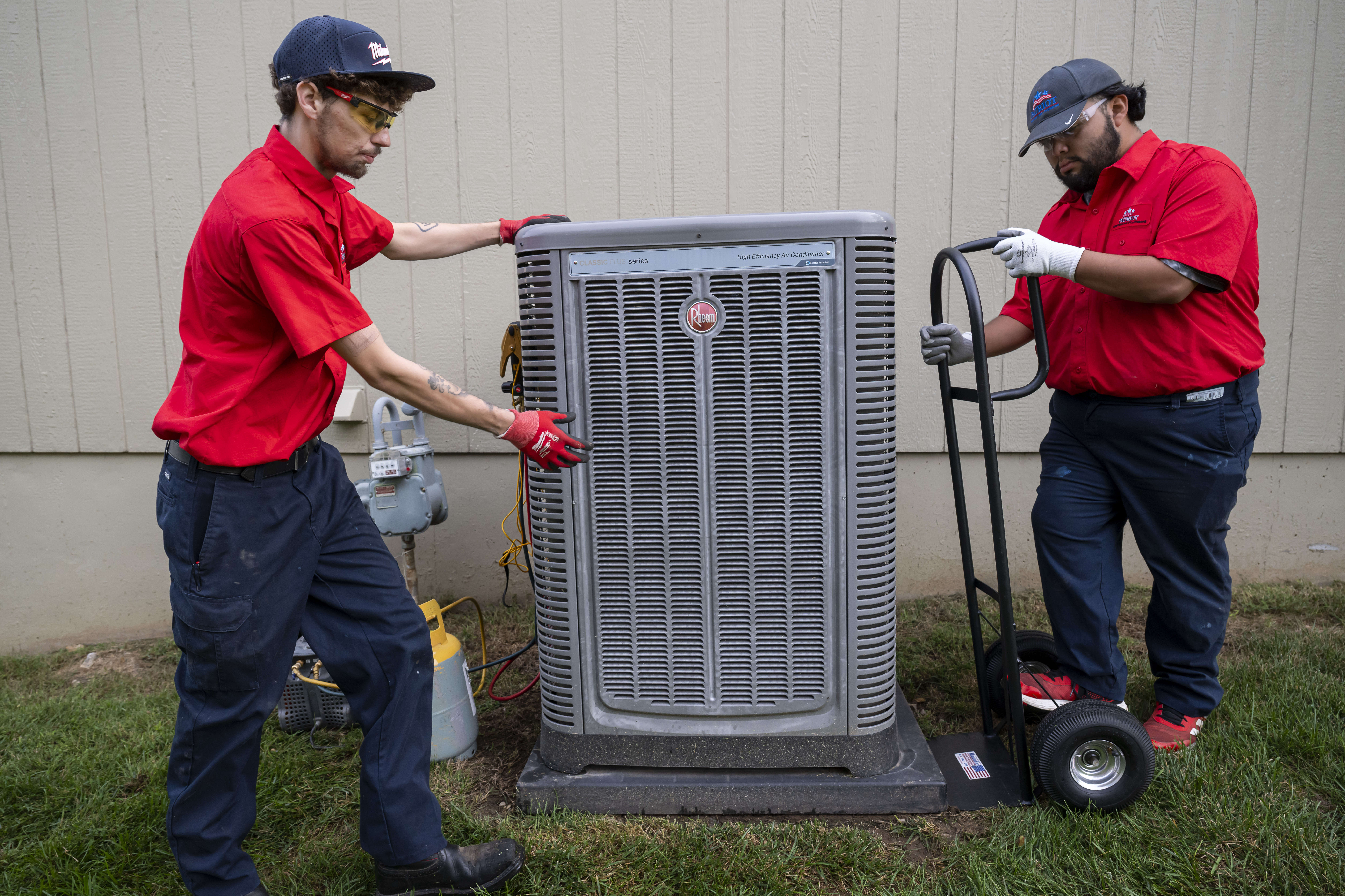 Two Patriot Heating & AC technicians installing an outdoor air conditioning unit