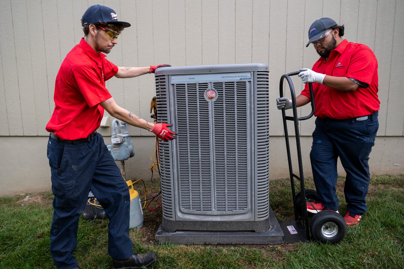 Two Patriot Heating & AC technicians installing an outdoor air conditioning unit