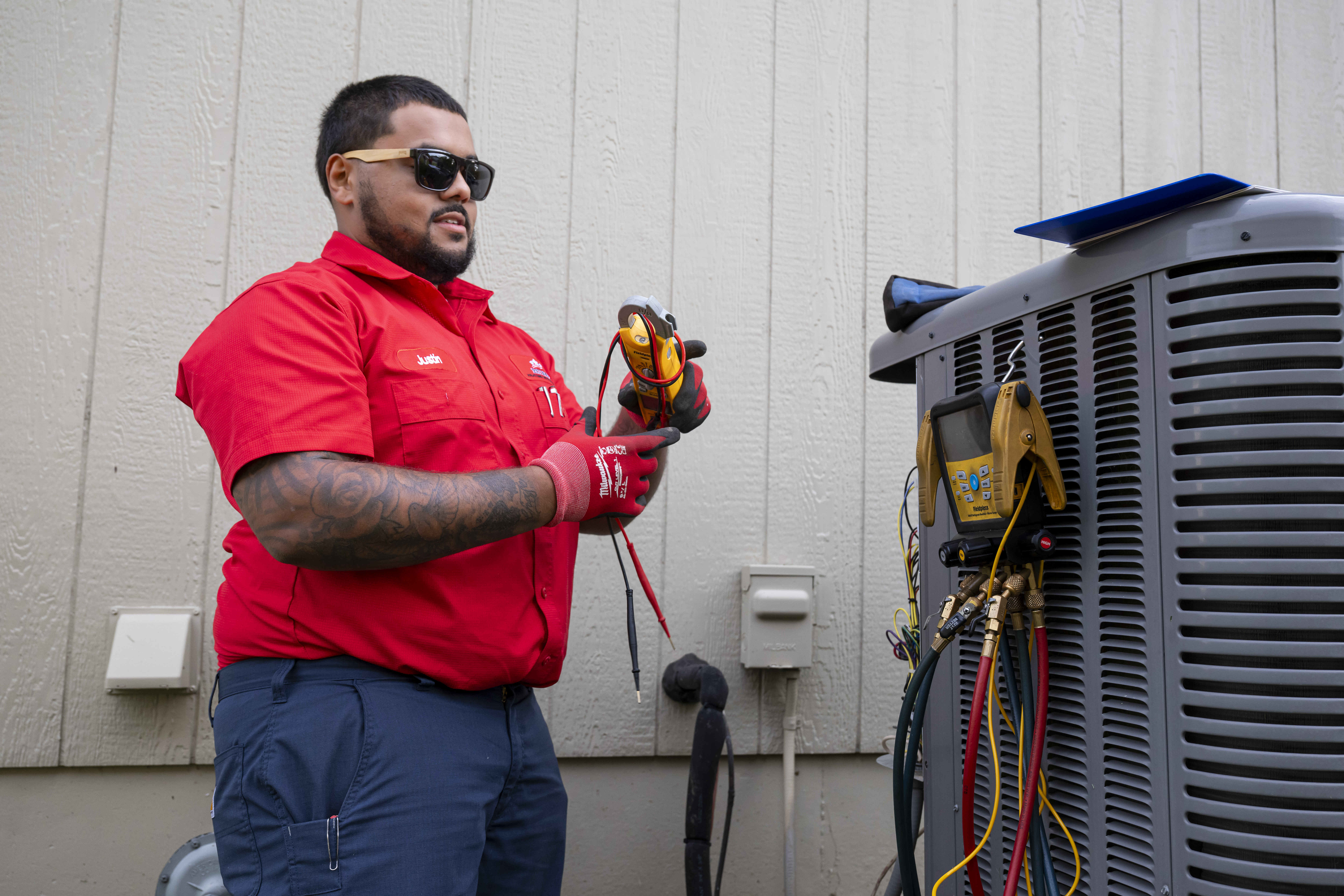 Patriot Heating & AC technician testing an outdoor HVAC unit with a meter