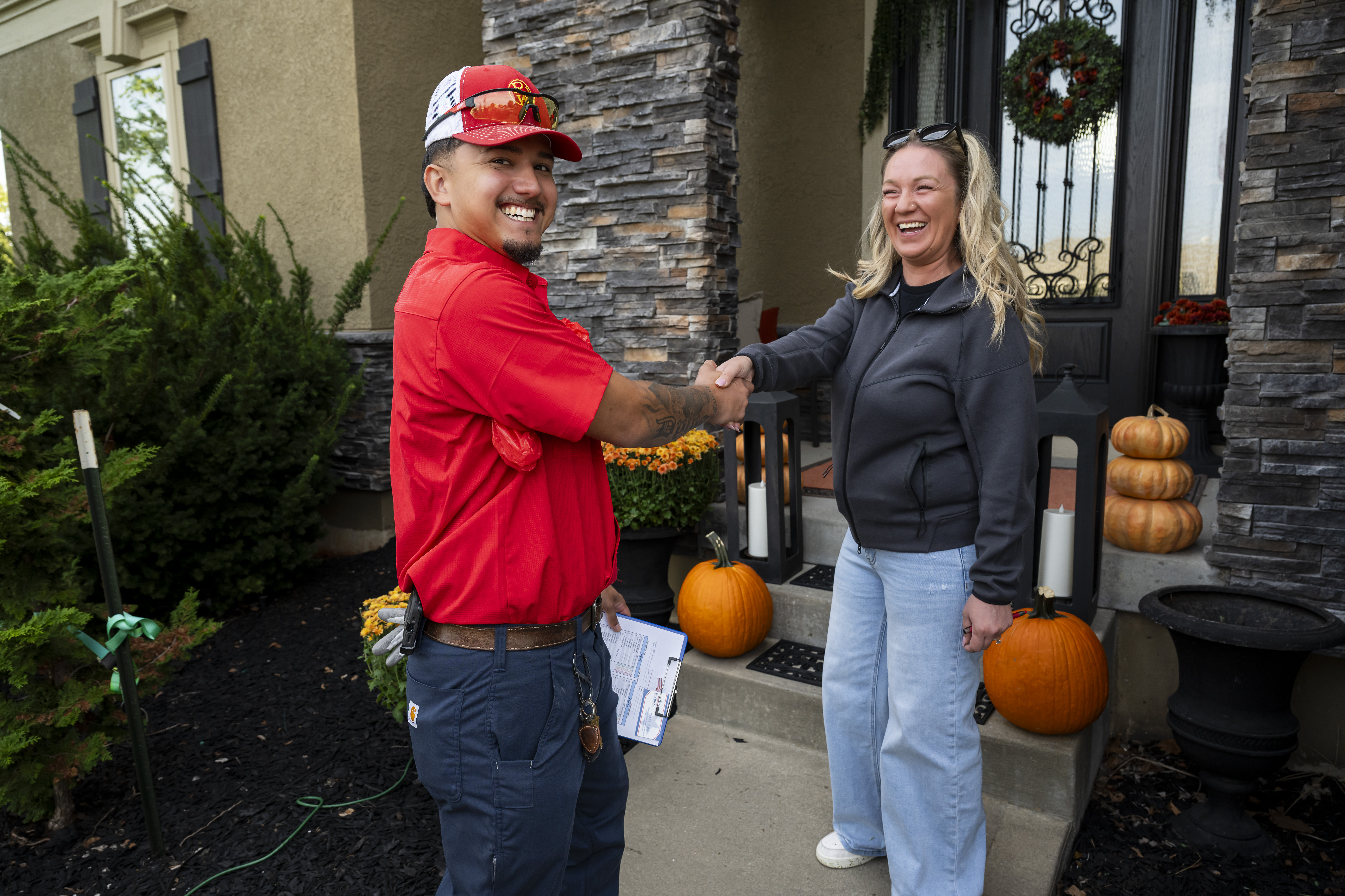 Patriot Heating & AC technician shaking hands with a homeowner at her front door