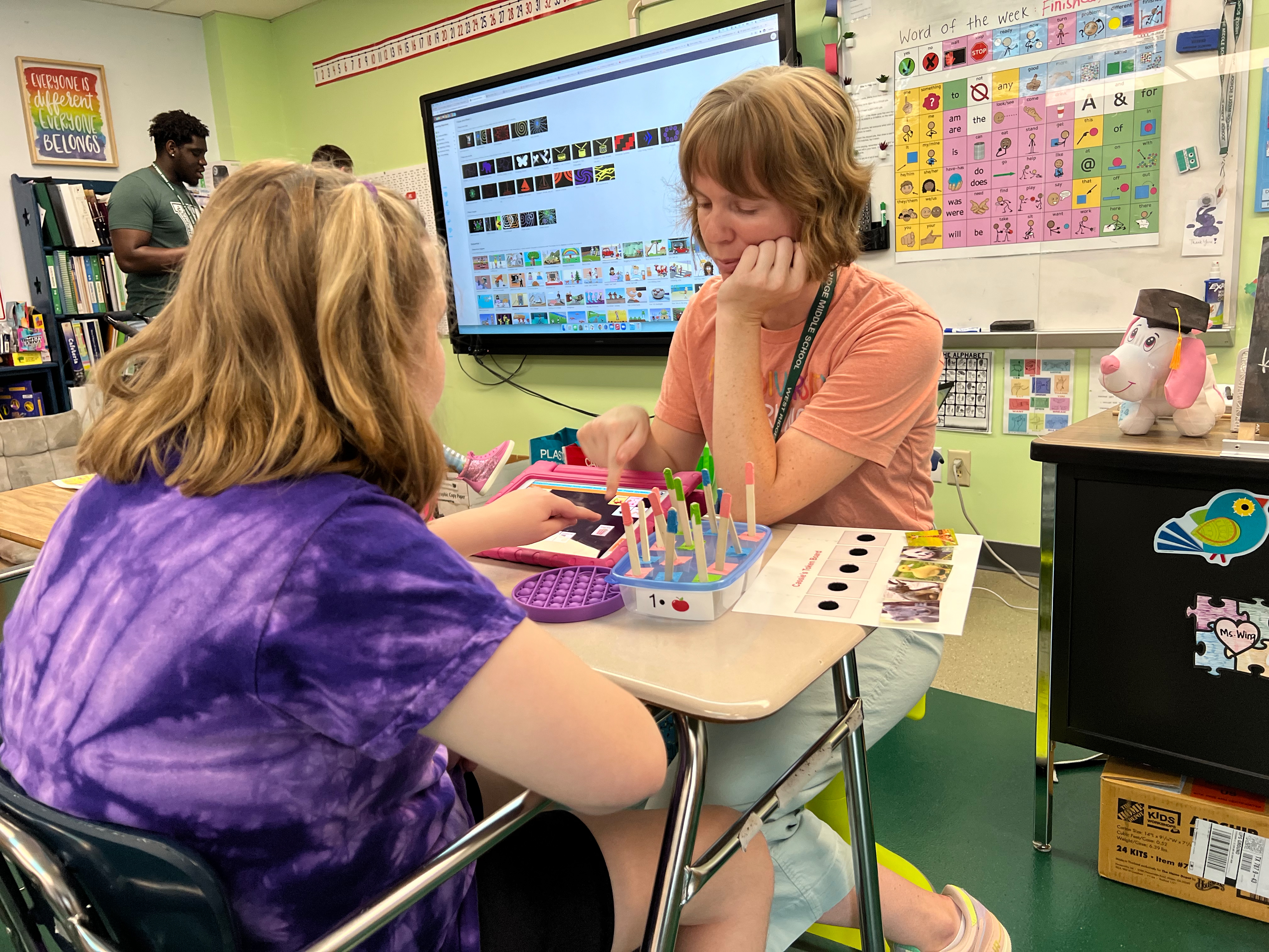 staff member assisting student with ipad in classroom
