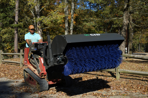 skid steer broom sweeping dirt on driveway, skid steer broom 48 inch width close up, skid steer broom clearing snow on sidewalk