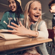 Girl missing front teeth smiling with book open