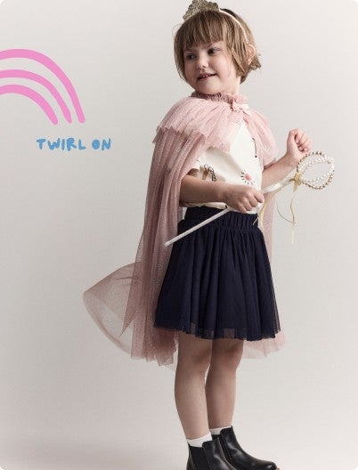 little girl with cape and scepter dressed in a shirt and skirt