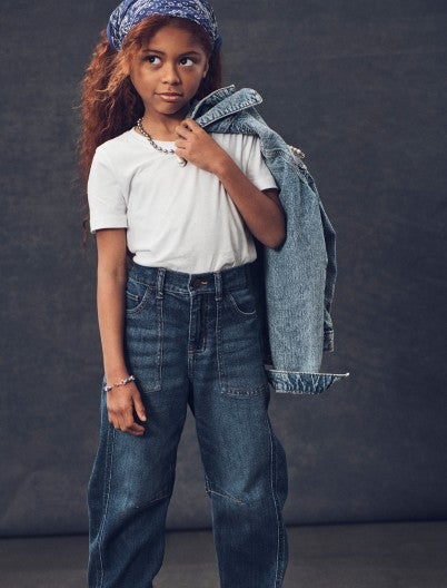 girl holding a denim jacket and wearing trending jeans