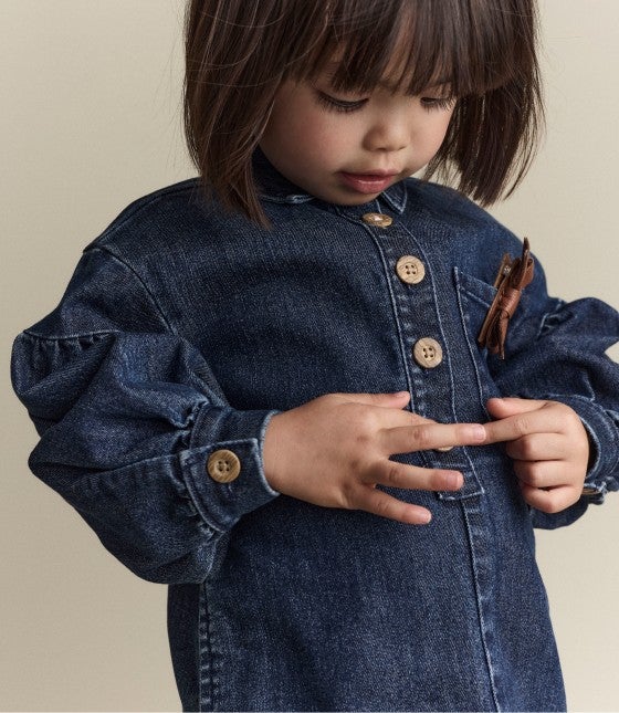 little girl looking at large buttons on her shirt