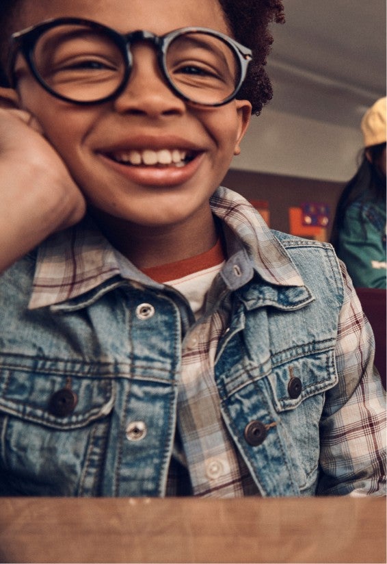 boy with glasses and denim vest