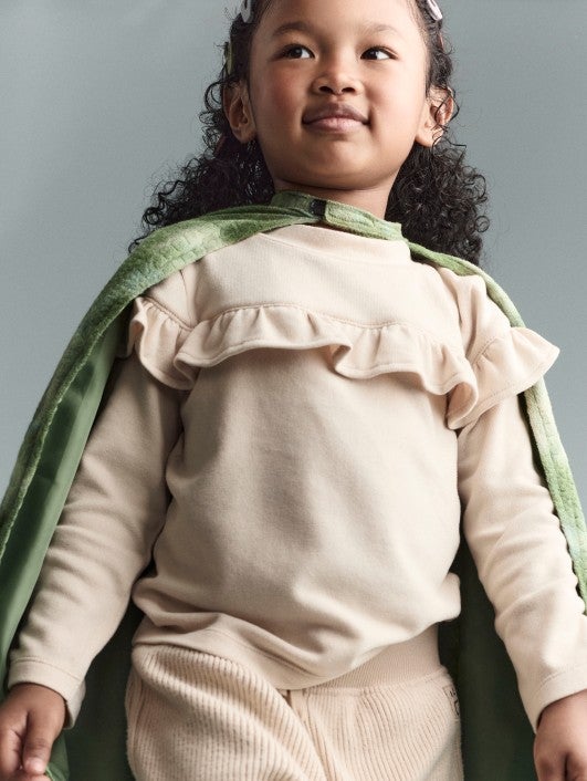 girl wearing a green cape and cream colored shirt