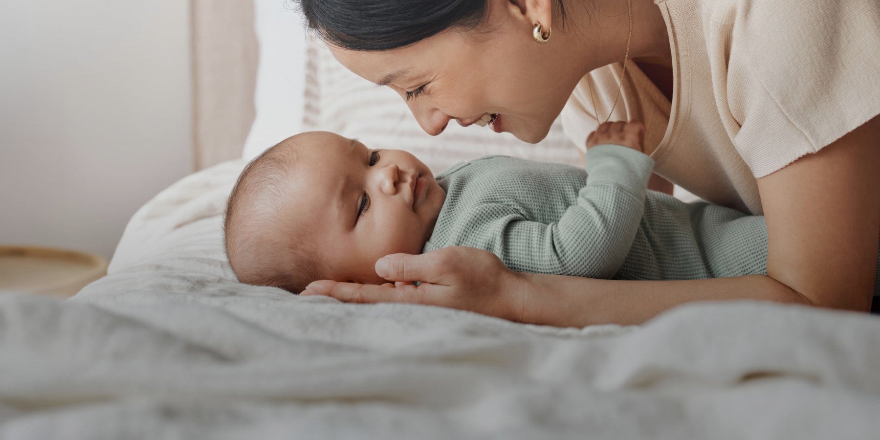 baby laying on bed with mom