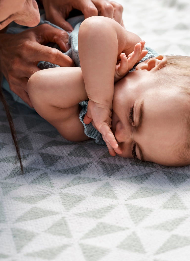 baby laying down covering face