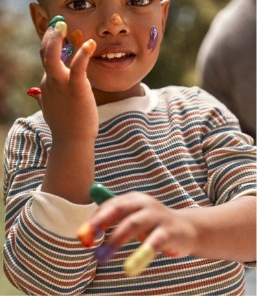 kid in knitwear, with paint on hands