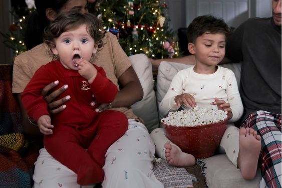 kids sitting on the couch with their parents in christmas pajamas