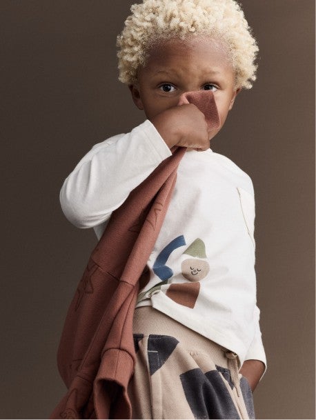boy holding sweatshirt over mouth