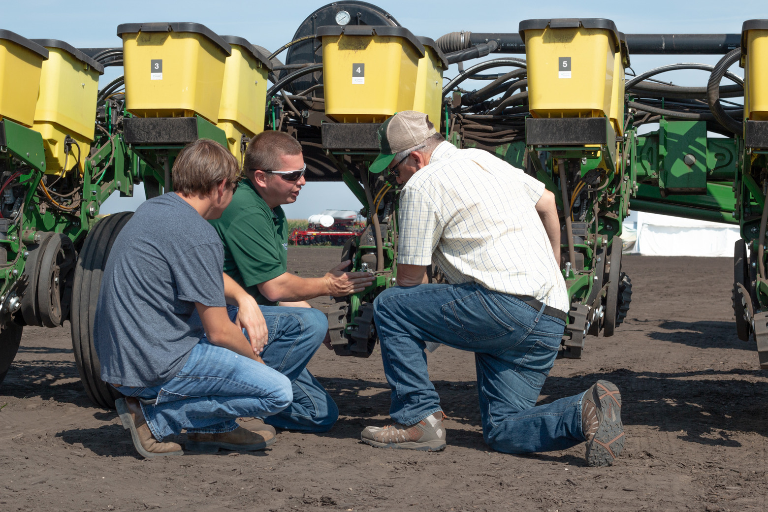 Farmers behind a planter looking at technology.