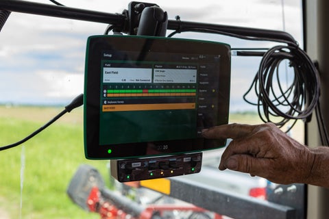 A farmer points to the 20|20 as he sets up the monitor for planting soybeans