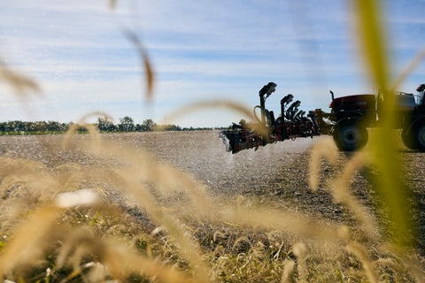Red sprayer equipped with SymphonyVision and SmokeRow spraying weeds at the field edge with a secondary tank chemistry.