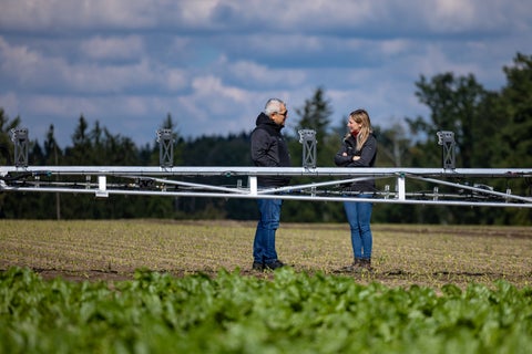 Two farmers standing behind a sprayer arm
