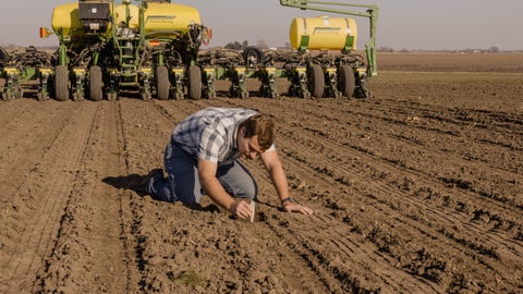 Farmer digging for seed behind the planter