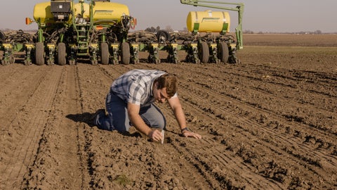 Precision Planting employee digging seed trench for seed depth behind a John Deere planter equipped with Precision Planting FurrowForce