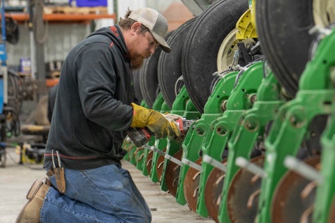 Precision Planting Premier Dealer working on planter row units in a shop.