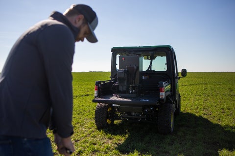 An agronomist collects soil samples in a field next to a UTV with GeoPress in the rear bed.