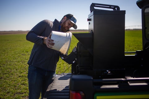 An agronomist loads GeoPress on the back of an ATV in a field.