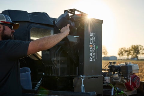 An agronomist loads GeoPress on the back of an ATV in a field.