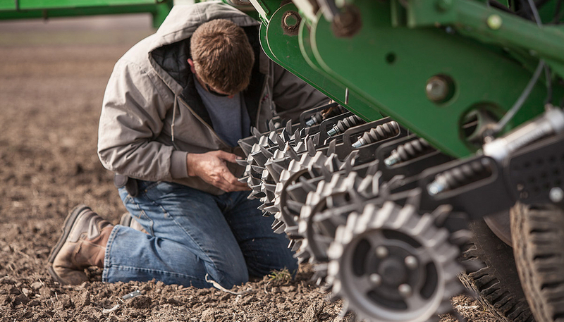 A farmer adjusting a row cleaner while in the field.