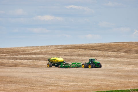 John Deere tractor and air cart in an open field.