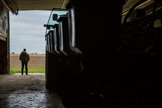 Farmer standing in the doorway of his farm shop with a planter in the foreground. 