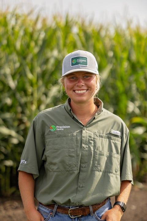 Precision Planting employee smiling in front of a corn field.