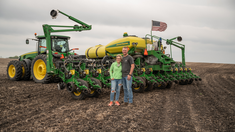 Ryan and Emily Ponwith are corn and soybean farmers in south central Minnesota standing in front of their John Deere 1770NT planter