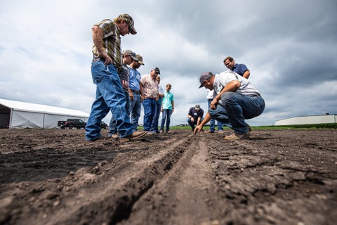 Des agriculteurs observent un sillon ouvert à la ferme PTI avec les agronomes de Precision Planting.