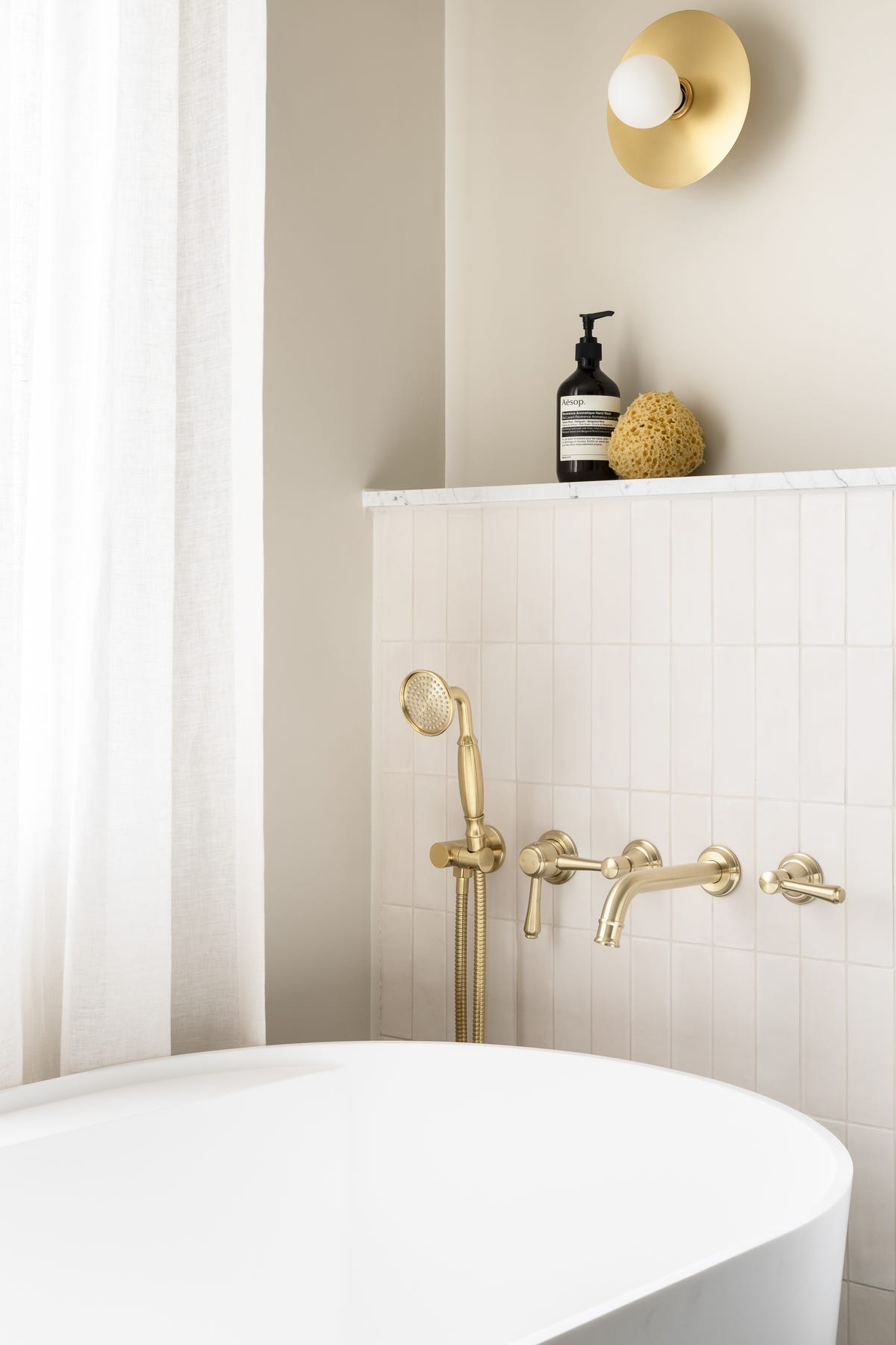 Brushed brass tapware and hand shower in a Studio Milne bathroom