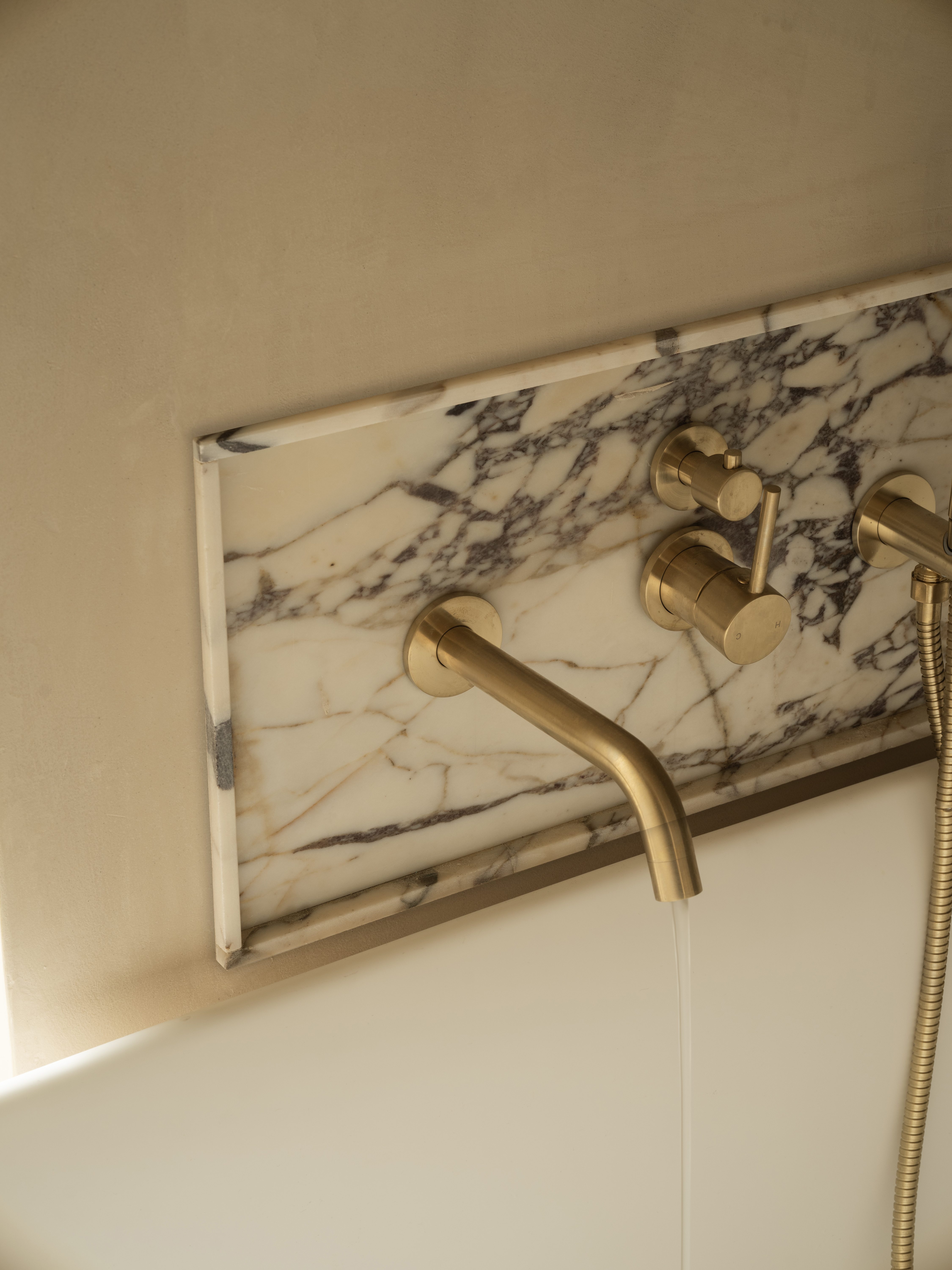 Marble bath surround with brushed brass tapware